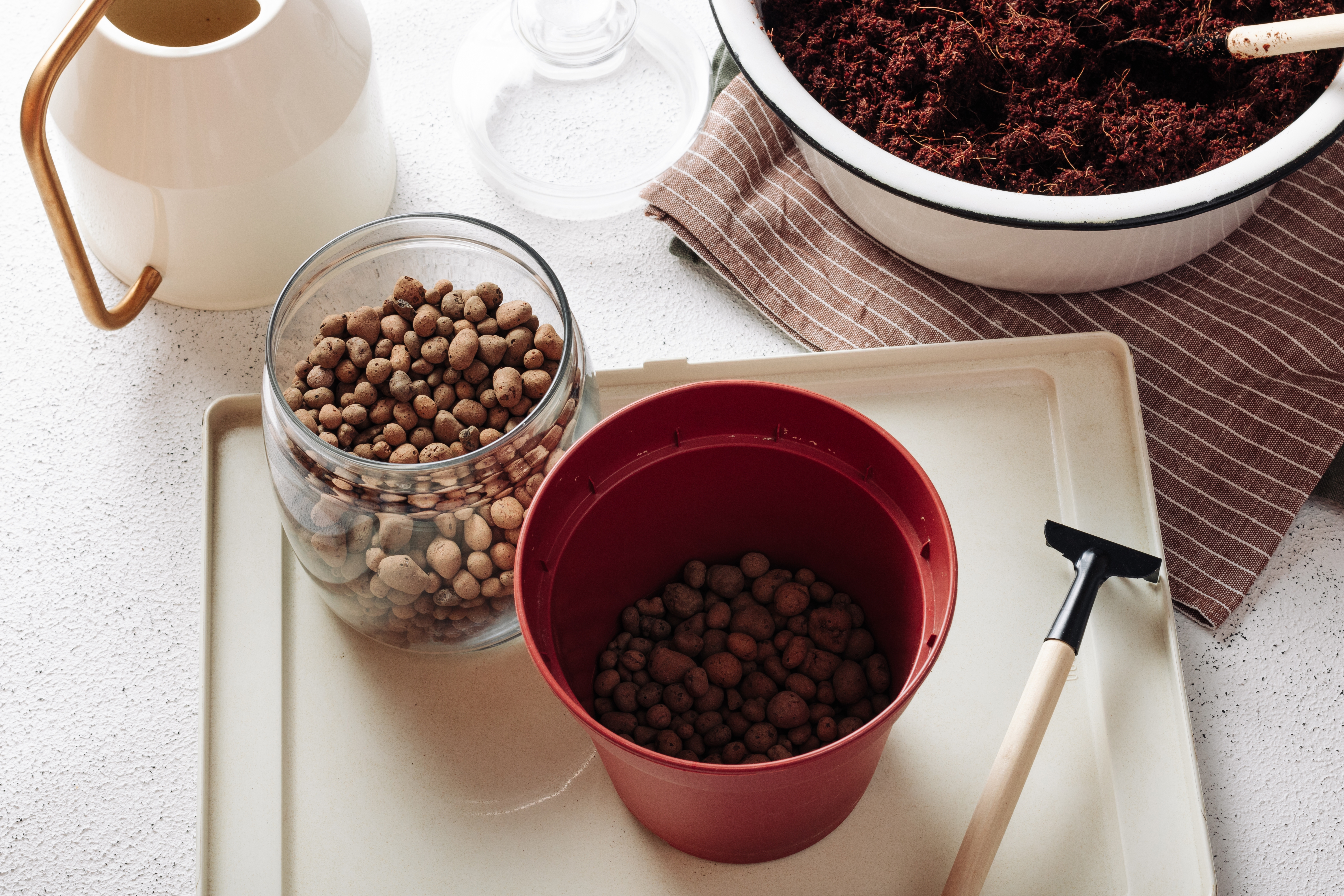 Flower pot with drainage pebbles used to explain why bottom layers do not fix overwatering.