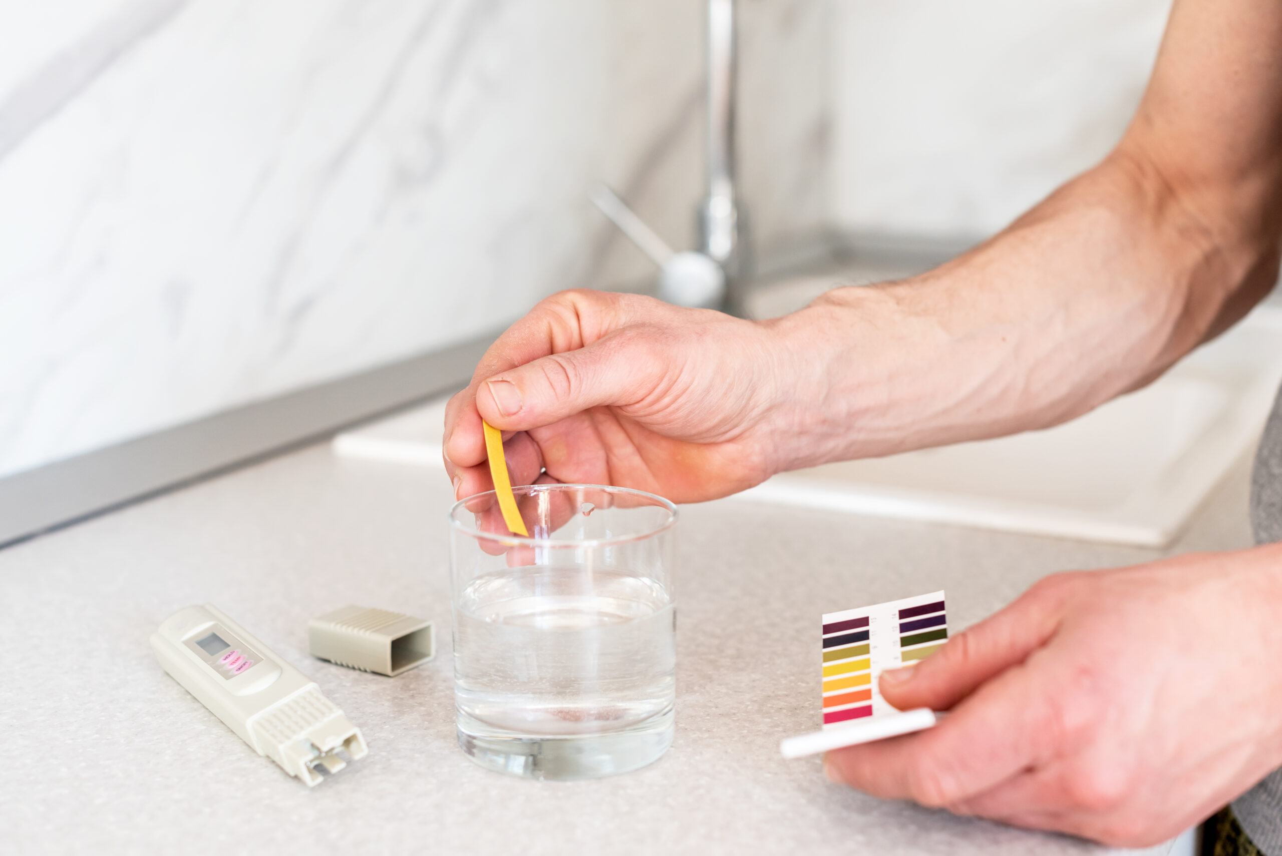 Glass of water, quality tester and universal litmus ph tester with color scale. Measuring the characteristics of drinking water. Tap water quality analyzer . Checking the purity of water at home.