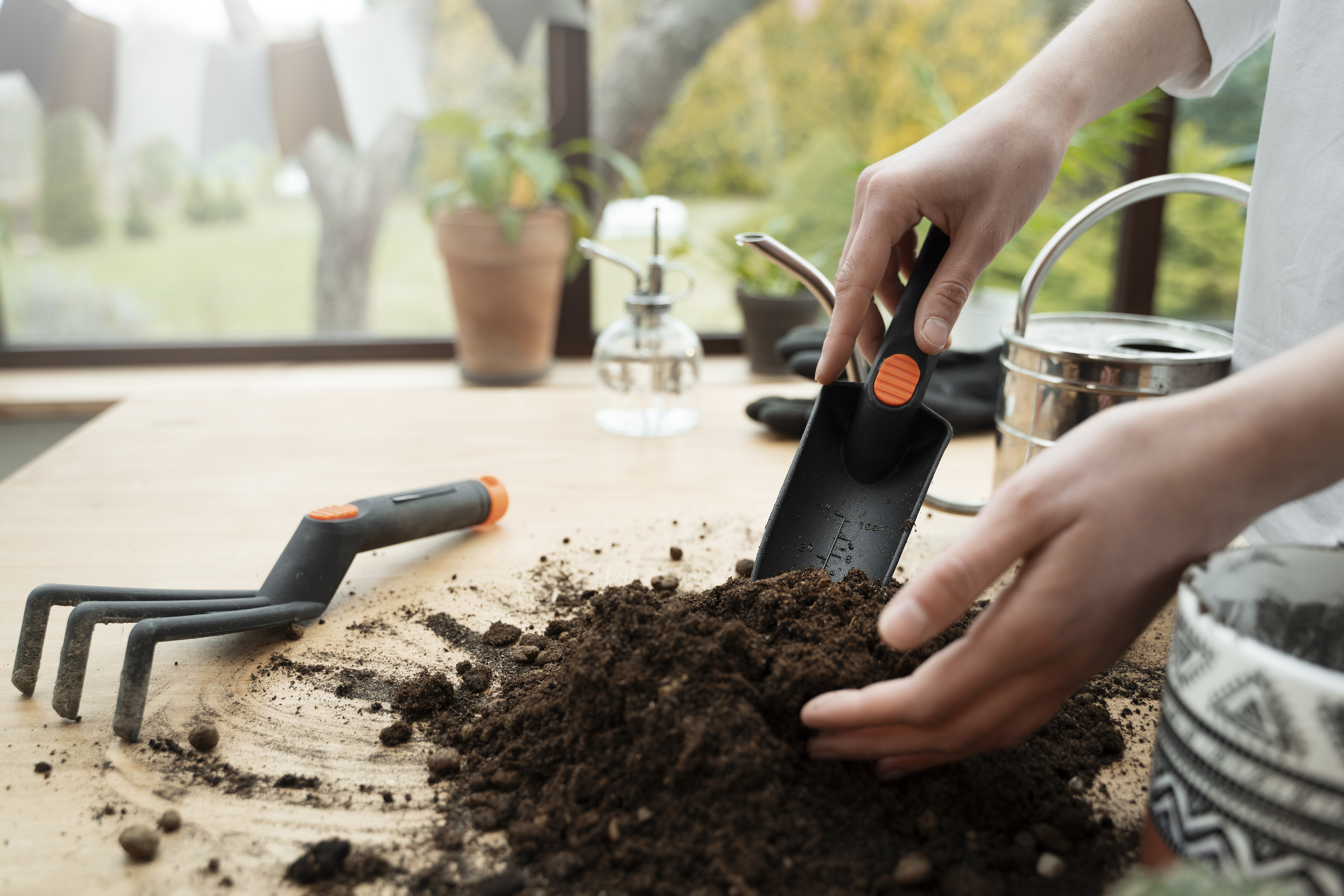 Hand using a gardening scoop with compost tea material for biological soil support.