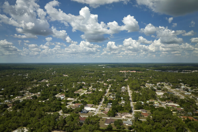 Aerial landscape view of suburban private houses between green palm trees in Florida quiet rural area.