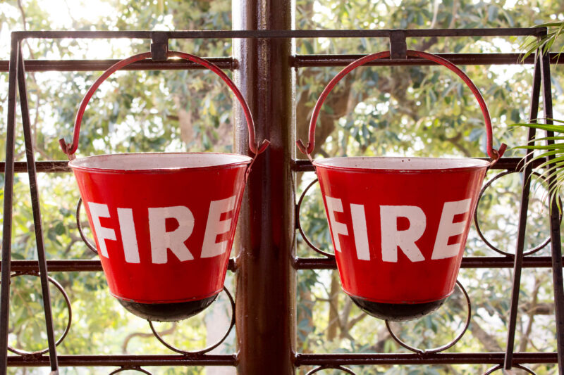 Red fire bin contain the sand hang on metal rack